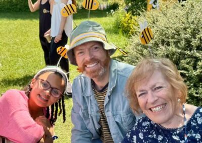 Three people wearing bee boppers smiling outdoors.
