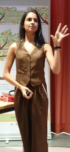 Zeenat A. speaking at a cognitive health event, holding a microphone.